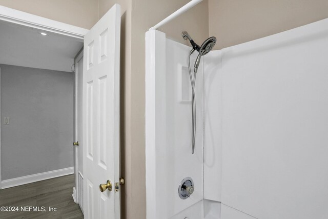 interior details with bathtub / shower combination and hardwood / wood-style floors