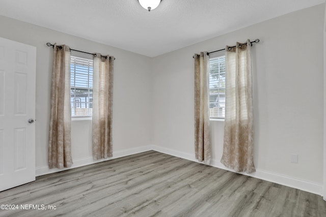 unfurnished room featuring light hardwood / wood-style floors and a textured ceiling