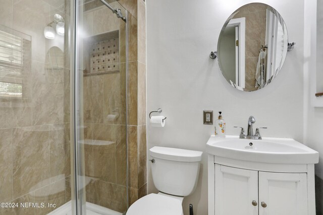 bathroom featuring toilet, a shower with door, and vanity