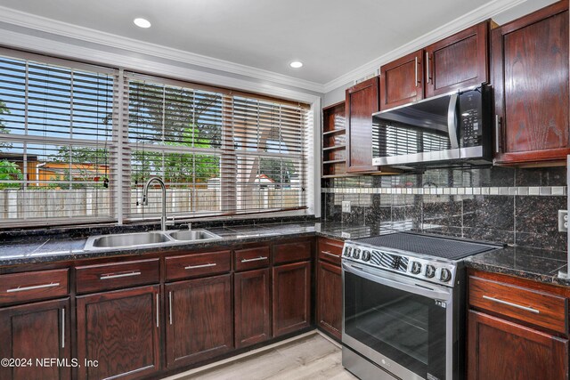 kitchen with appliances with stainless steel finishes, backsplash, ornamental molding, light hardwood / wood-style flooring, and sink