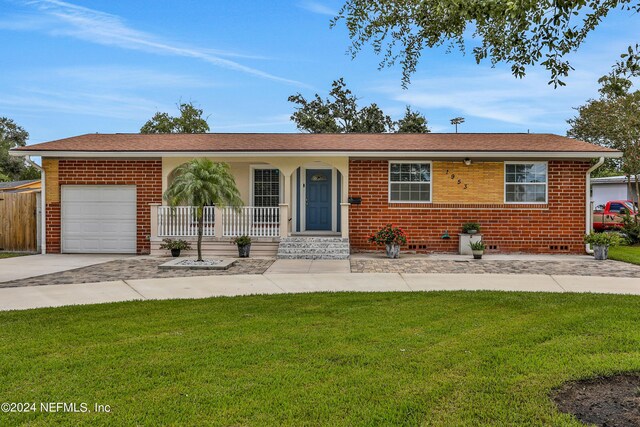 ranch-style house featuring a front yard, covered porch, and a garage