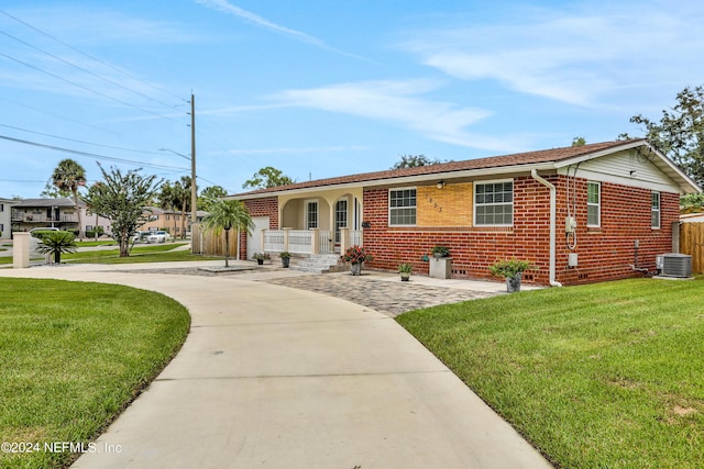 ranch-style home with a front yard, covered porch, and cooling unit