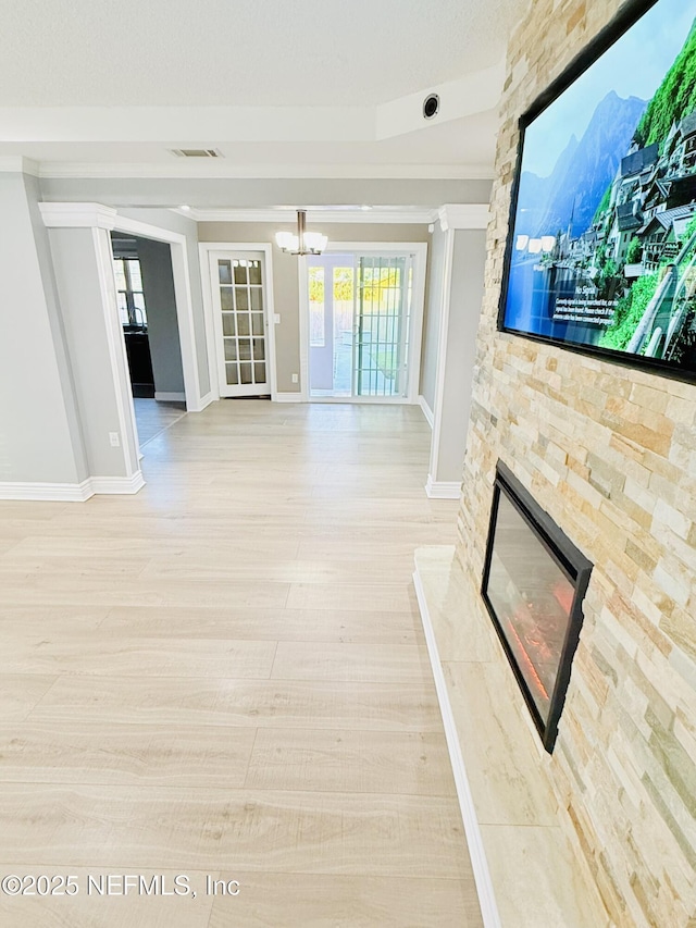 unfurnished living room featuring an inviting chandelier, a fireplace, light hardwood / wood-style floors, and plenty of natural light