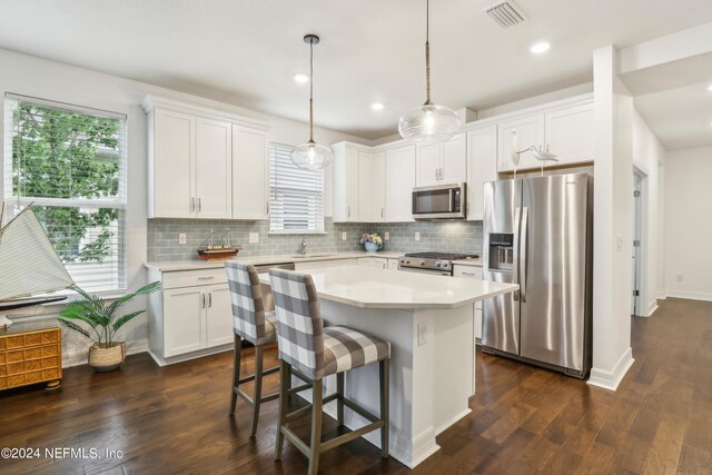 kitchen with a kitchen island, pendant lighting, dark hardwood / wood-style floors, and stainless steel appliances