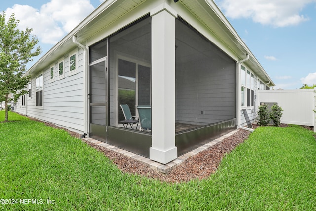 back of property featuring a sunroom and a lawn