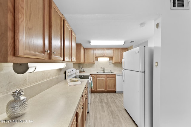 kitchen with white appliances, sink, decorative backsplash, and light wood-type flooring