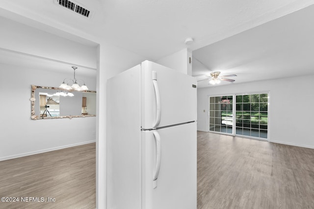 kitchen with pendant lighting, wood-type flooring, ceiling fan with notable chandelier, and white fridge