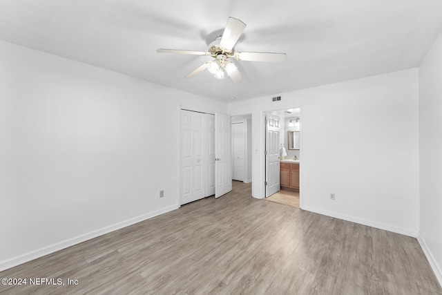 unfurnished bedroom with ceiling fan, ensuite bathroom, and light wood-type flooring