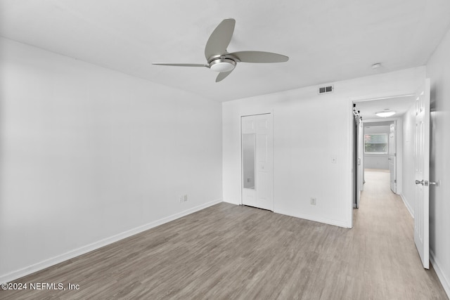 unfurnished bedroom with ceiling fan, light wood-type flooring, and a closet