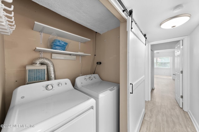 washroom with a barn door, separate washer and dryer, and light hardwood / wood-style flooring