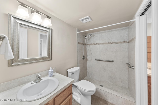 bathroom featuring vanity, tiled shower, and toilet