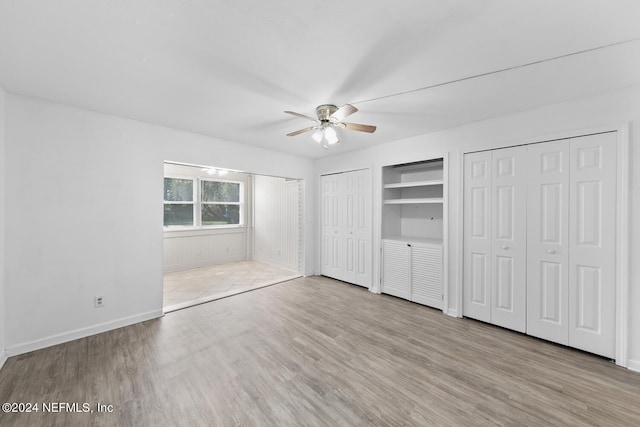 unfurnished bedroom with ceiling fan, light hardwood / wood-style flooring, and two closets