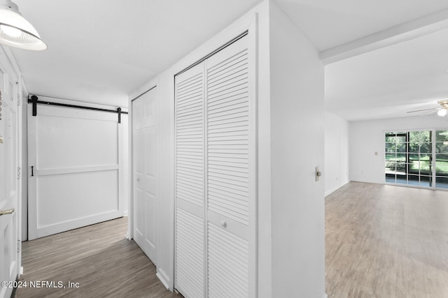 corridor with light hardwood / wood-style floors and a barn door