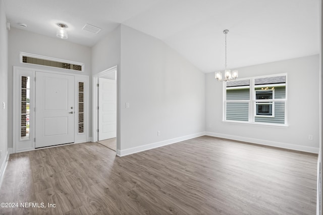 entrance foyer featuring lofted ceiling, hardwood / wood-style floors, a wealth of natural light, and a chandelier