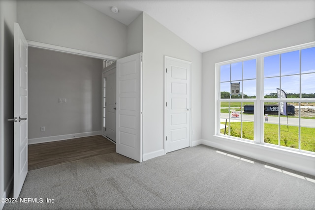 unfurnished bedroom with dark carpet and vaulted ceiling