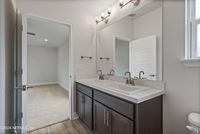 full bath with double vanity, a sink, visible vents, and baseboards