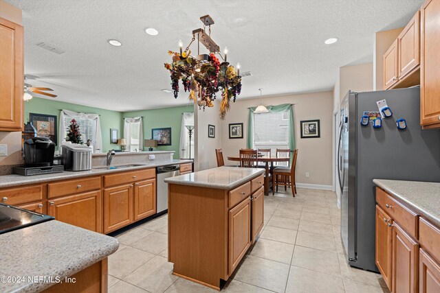 kitchen featuring pendant lighting, light tile patterned floors, a center island, stainless steel appliances, and sink