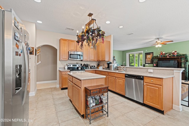 kitchen with stainless steel appliances, sink, kitchen peninsula, light tile patterned flooring, and ceiling fan