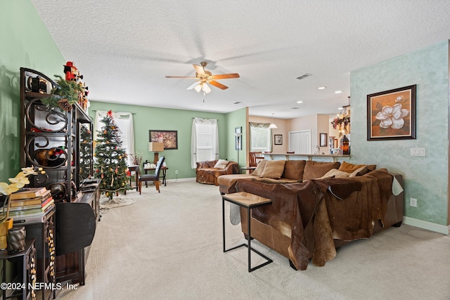 living room with light colored carpet, a textured ceiling, and ceiling fan