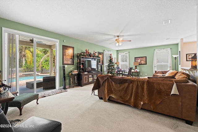 living room featuring a textured ceiling, carpet flooring, and ceiling fan