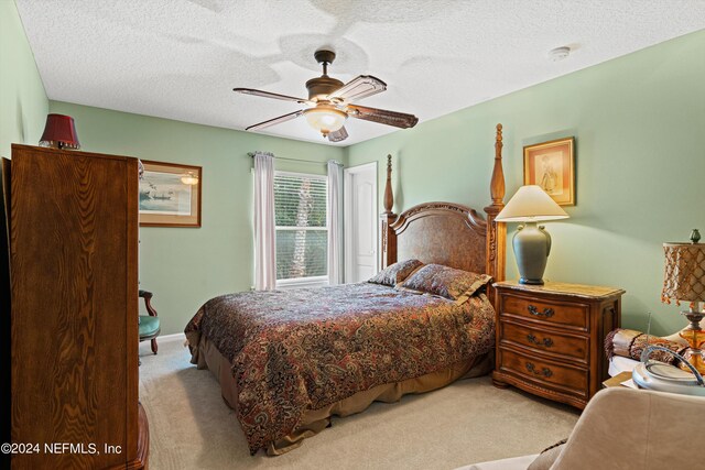 bedroom featuring a textured ceiling, light colored carpet, and ceiling fan