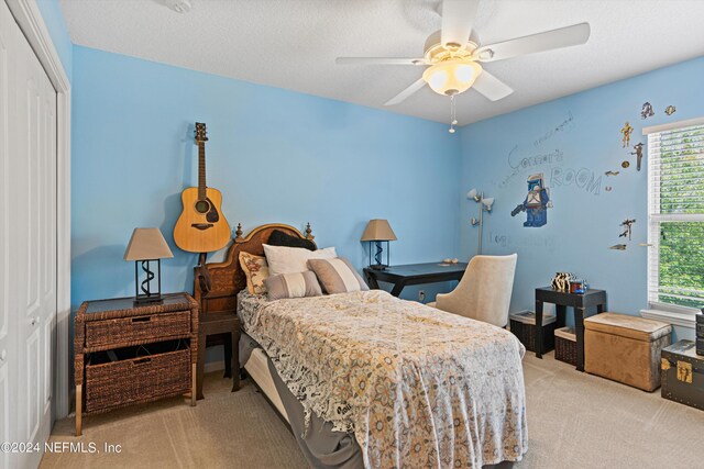 carpeted bedroom with a closet, ceiling fan, and a textured ceiling