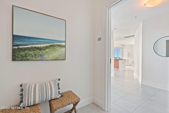 corridor featuring baseboards and light tile patterned floors