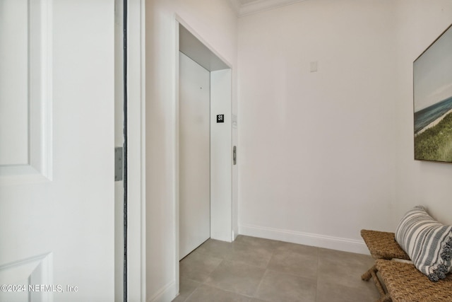 hall with baseboards, light tile patterned flooring, and elevator