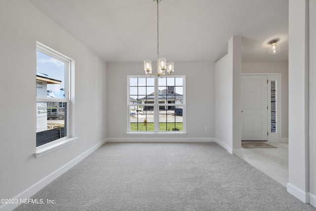 unfurnished dining area featuring baseboards, a notable chandelier, and light colored carpet