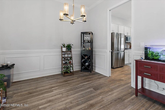 dining area with crown molding, hardwood / wood-style flooring, and an inviting chandelier