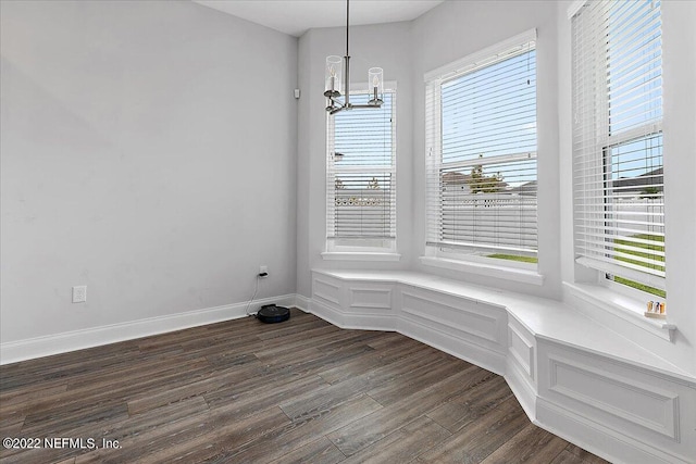 unfurnished dining area featuring a notable chandelier, wood-type flooring, and a healthy amount of sunlight