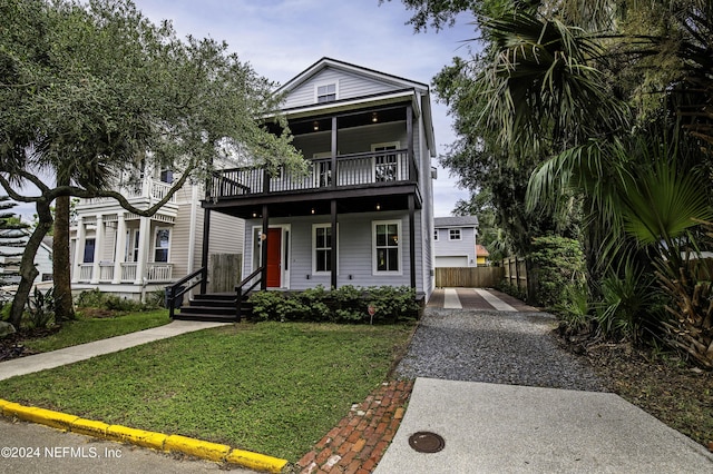 view of front facade featuring a front yard, covered porch, fence, and a balcony