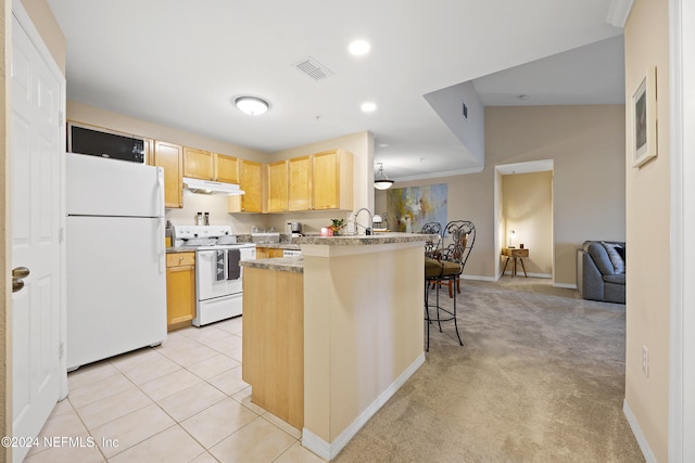 kitchen with kitchen peninsula, white appliances, a breakfast bar area, light carpet, and light brown cabinetry