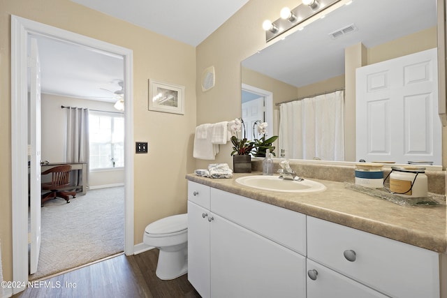 bathroom with hardwood / wood-style floors, vanity, ceiling fan, and toilet