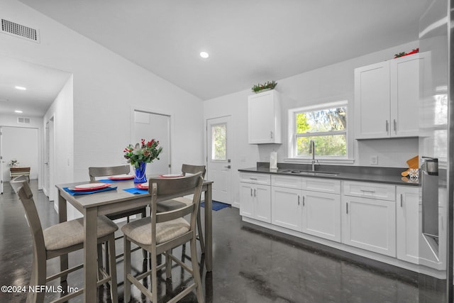 kitchen featuring white cabinets, stainless steel fridge with ice dispenser, sink, and vaulted ceiling