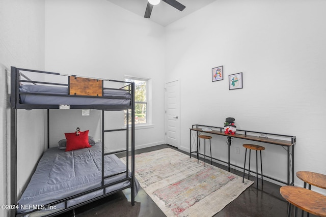 bedroom with a towering ceiling, concrete floors, and ceiling fan