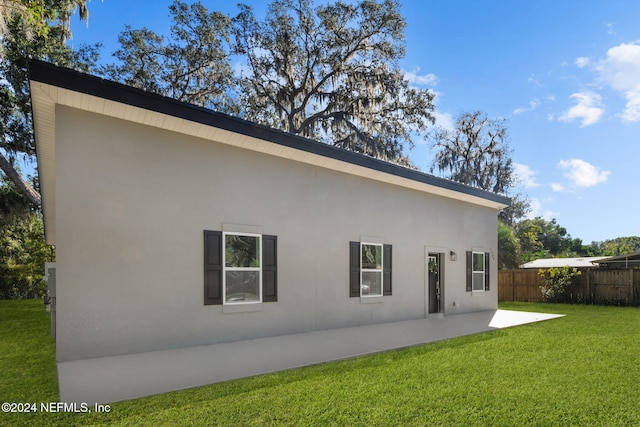 rear view of property featuring a lawn and a patio area