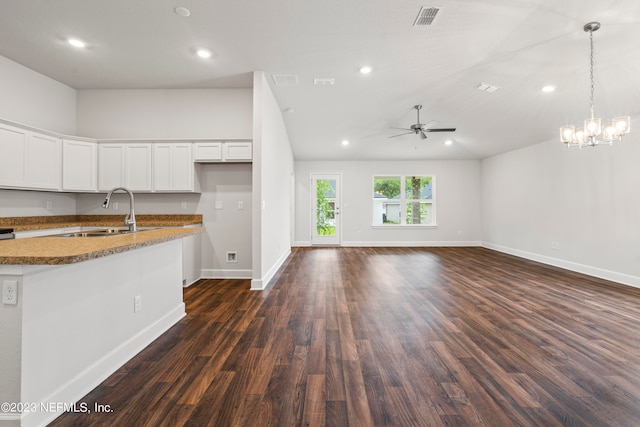 kitchen featuring white cabinets, dark wood-type flooring, ceiling fan with notable chandelier, hanging light fixtures, and sink