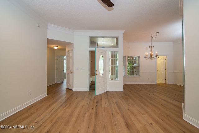 entryway with a textured ceiling, light wood-type flooring, ornamental molding, and a chandelier