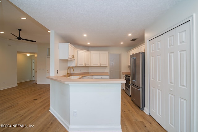 kitchen featuring light hardwood / wood-style flooring, ceiling fan, kitchen peninsula, white cabinets, and stainless steel appliances