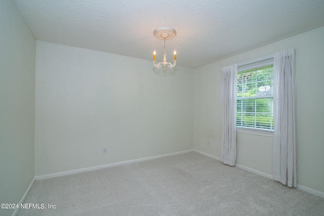 unfurnished room featuring a notable chandelier, a textured ceiling, and carpet