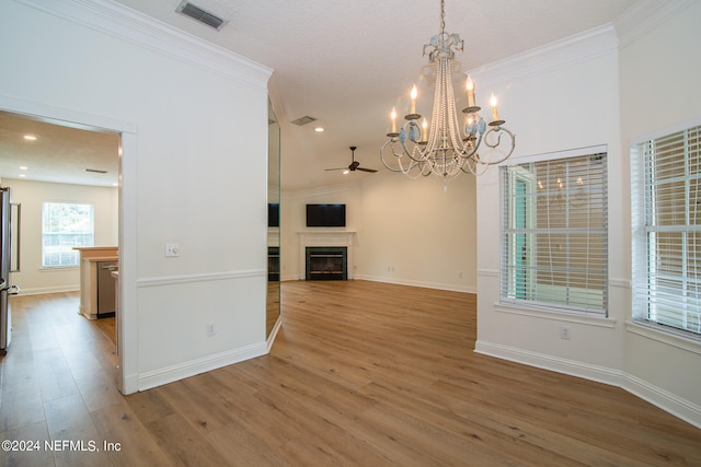 unfurnished living room with ceiling fan with notable chandelier, ornamental molding, and hardwood / wood-style floors