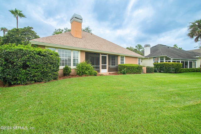 back of property featuring a sunroom and a lawn