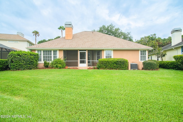 rear view of house featuring central AC, a sunroom, and a yard