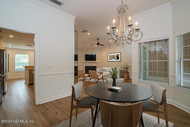 dining room featuring ceiling fan with notable chandelier, crown molding, and wood-type flooring