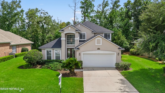 view of property with a garage, a front lawn, and central AC