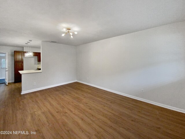 unfurnished living room with dark wood-type flooring and a notable chandelier