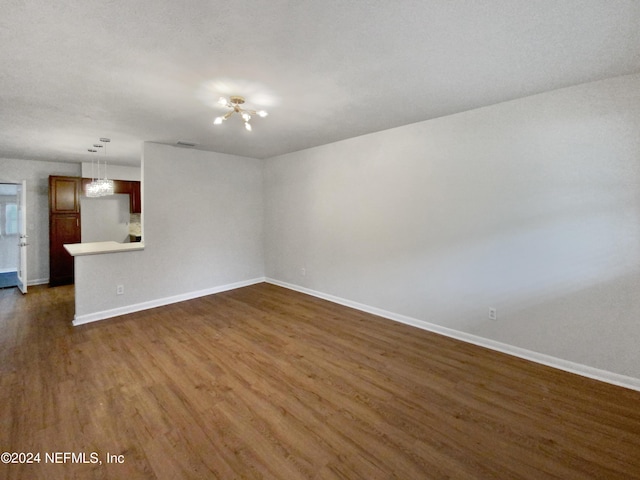 spare room with dark wood-type flooring and a chandelier