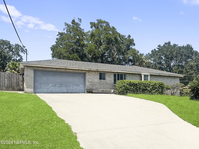 ranch-style house with an attached garage, brick siding, fence, concrete driveway, and a front lawn