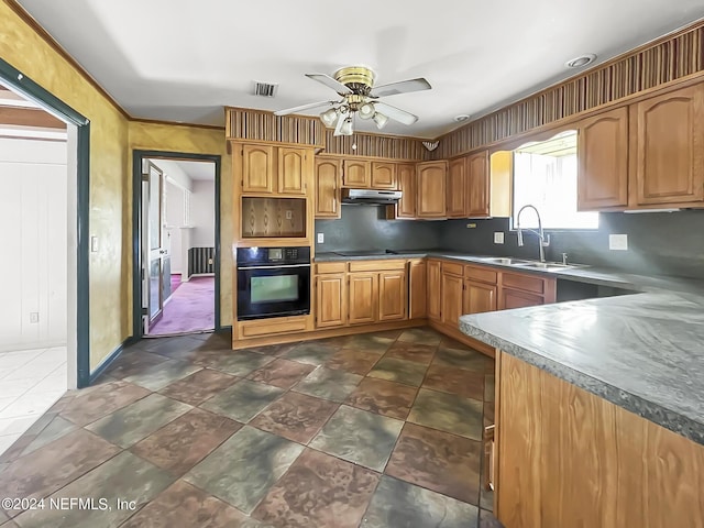 kitchen featuring under cabinet range hood, a sink, visible vents, black oven, and radiator heating unit